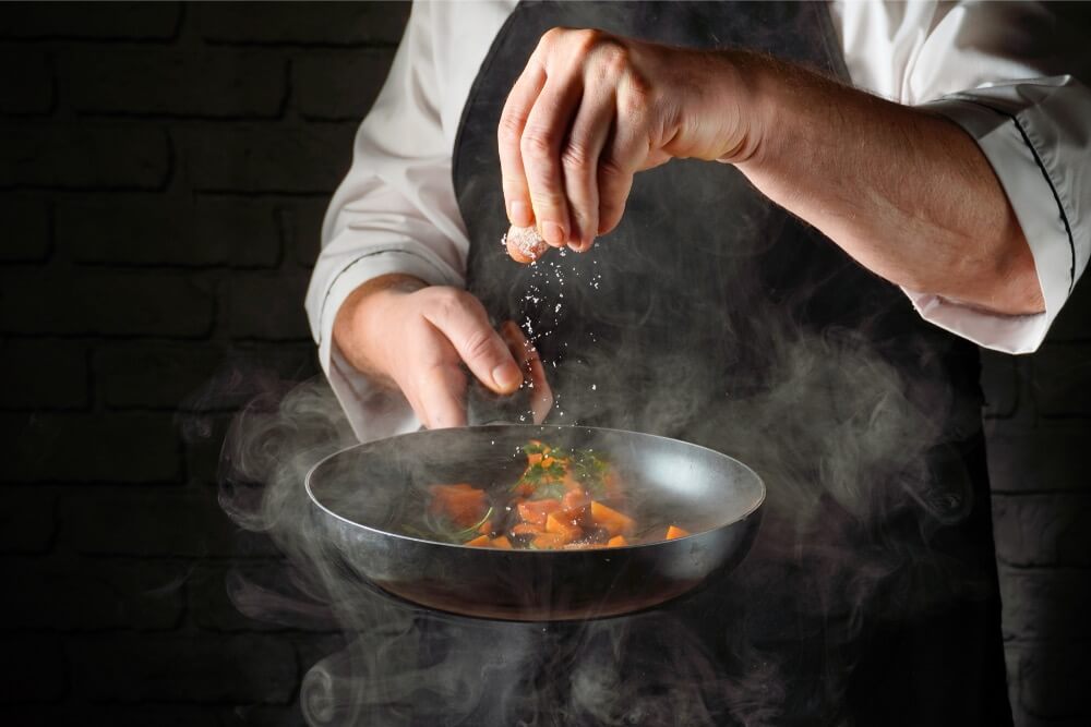 Wspólna praca dietetyka i kucharza przy blacie z produktami paleo i keto, zapewniająca, że catering dietetyczny jest jednocześnie zdrowy i smaczny.